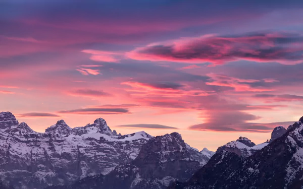 4K Ultra HD wallpaper showcasing the Dolomites in the Alps under a vibrant pink and purple sunset sky, highlighting the rugged mountain peaks and natural beauty.