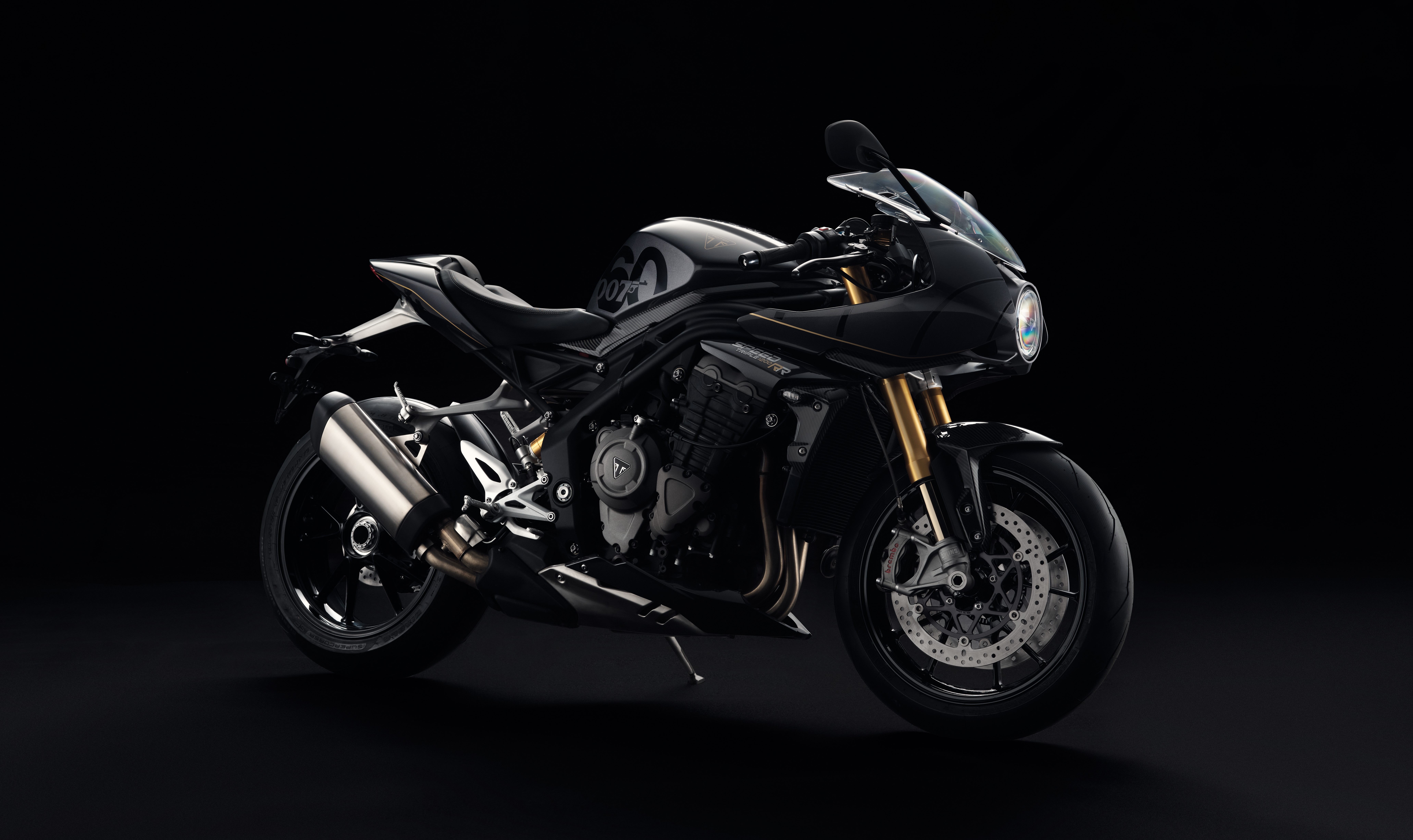 HD desktop wallpaper featuring the Triumph Speed Triple 1200 RR Bond Edition motorcycle against a dark background.