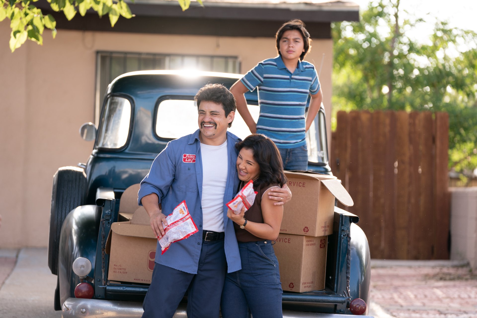 Happy family with Flamin' Hot snacks standing by vintage truck, HD desktop wallpaper background.