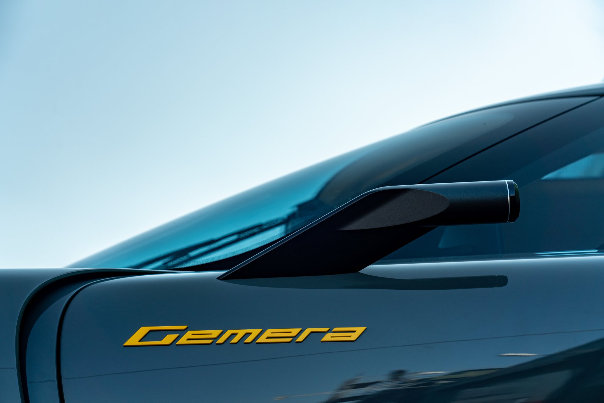 Close-up of a Koenigsegg Gemera vehicle, highlighting its sleek design and signature yellow lettering. This image serves as a stunning HD desktop wallpaper.