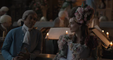 HD wallpaper of a chevalier-themed scene with two elegantly dressed individuals, one wearing a floral headdress, in a candlelit historical setting.