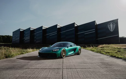 HD wallpaper featuring a Koenigsegg Gemera on a paved surface with a dark, stylized building in the background.