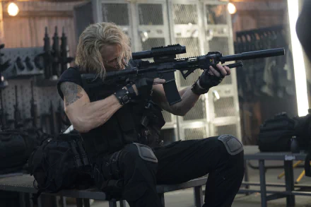 Dolph Lundgren is seen in an action-packed moment from Expend4bles, holding a rifle while preparing for a mission. This HD desktop wallpaper captures the intensity of the film.