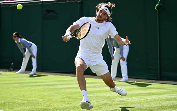 Stefanos Tsitsipas in action on the lush green grass of Wimbledon 2023, showcasing his athleticism and skill in this vibrant tennis sports wallpaper.