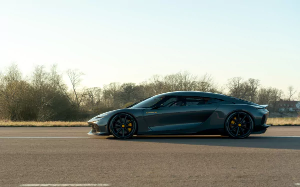 HD desktop wallpaper featuring a Koenigsegg Gemera sports car parked on an empty road with trees in the background, highlighting its sleek design and performance appeal.