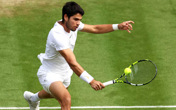 HD desktop wallpaper featuring a tennis player in action at Wimbledon 2023, poised to hit a backhand on the iconic grass court.