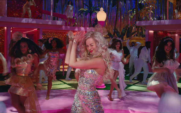 A vibrant scene from the movie *Barbie* (2023) featuring Margot Robbie dancing joyfully among a colorful cast, set against a dazzling party backdrop.