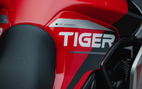 Close-up of the Triumph Tiger 900 GT Aragón motorcycle, showcasing its bold red design and distinctive TIGER branding. A striking HD desktop wallpaper for motorcycle enthusiasts.