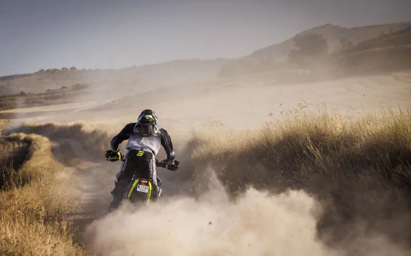 A Triumph Tiger 900 Rally Pro kicks up dust while navigating a rugged landscape, showcasing its powerful presence in this high-definition desktop wallpaper.