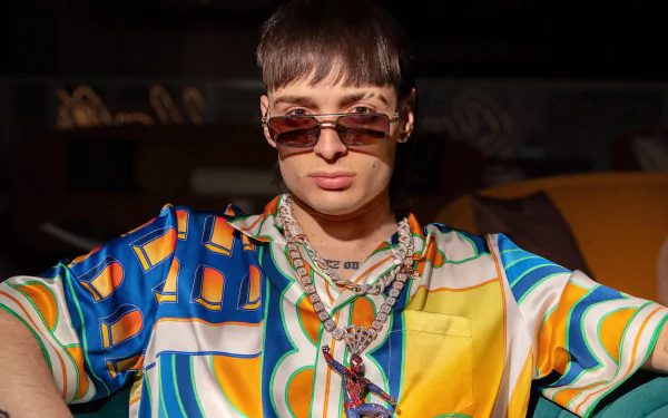 Stylish individual in colorful clothing and sunglasses posing confidently for a Peso Pluma-themed HD desktop wallpaper and background.