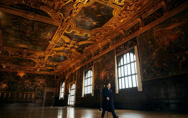 HD wallpaper of A Haunting in Venice theme featuring an atmospheric shot with a mysterious figure in an ornate, golden-lit room with classical paintings.