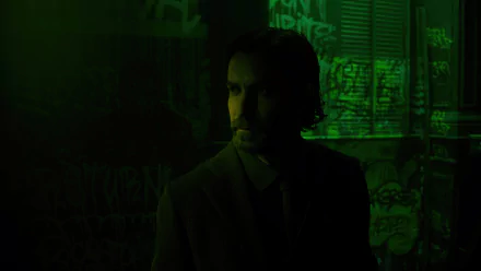 A dark and atmospheric HD wallpaper featuring a character from Alan Wake 2, standing in a shadowy environment illuminated by a green hue, evoking a sense of mystery.