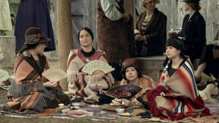 A cinematic HD wallpaper featuring a scene from Killers of the Flower Moon, with characters in period costumes sitting and holding fans, creating an evocative historical ambiance for a desktop background.