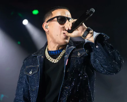 HD wallpaper of a performer in a glittering jacket singing into a microphone on stage, with bright stage lights in the background.