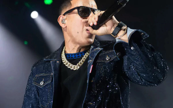 HD wallpaper of a performer in a glittering jacket singing into a microphone on stage, with bright stage lights in the background.