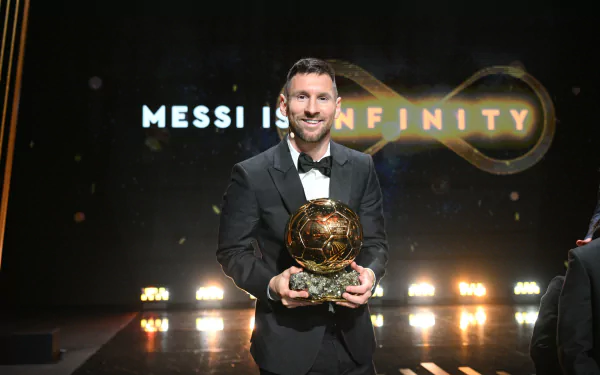 HD desktop wallpaper featuring a sports personality in a suit, holding a golden trophy at an award ceremony, with the caption Messi is Infinity in the background.