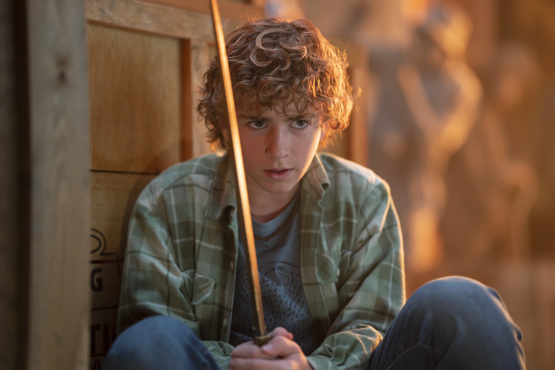Young male character from the TV show Percy Jackson and the Olympians holding a wooden rod, looking thoughtful, in a high-definition desktop wallpaper.
