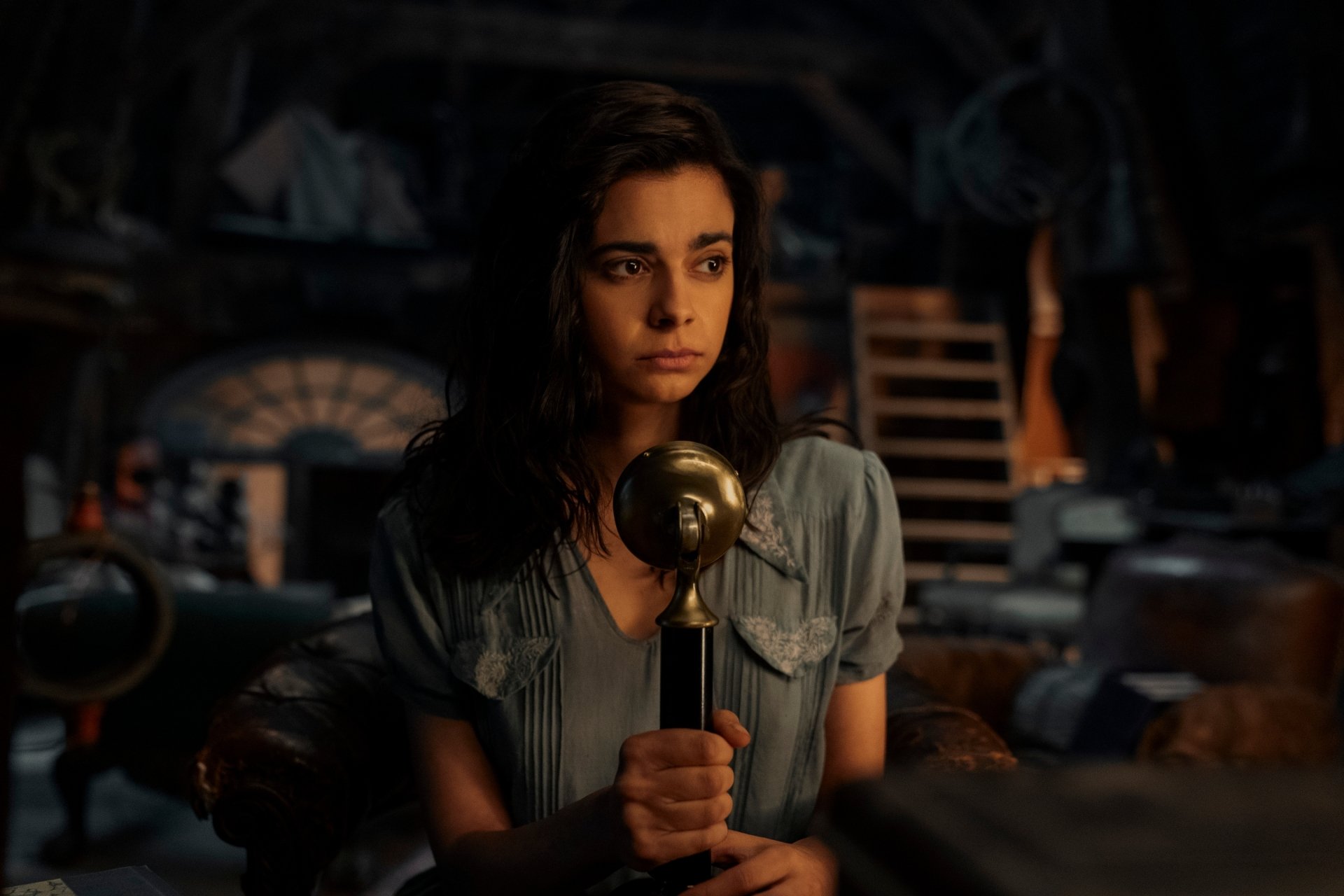 HD wallpaper featuring a scene from the TV show All the Light We Cannot See with a female character holding a microphone in a dimly lit room.