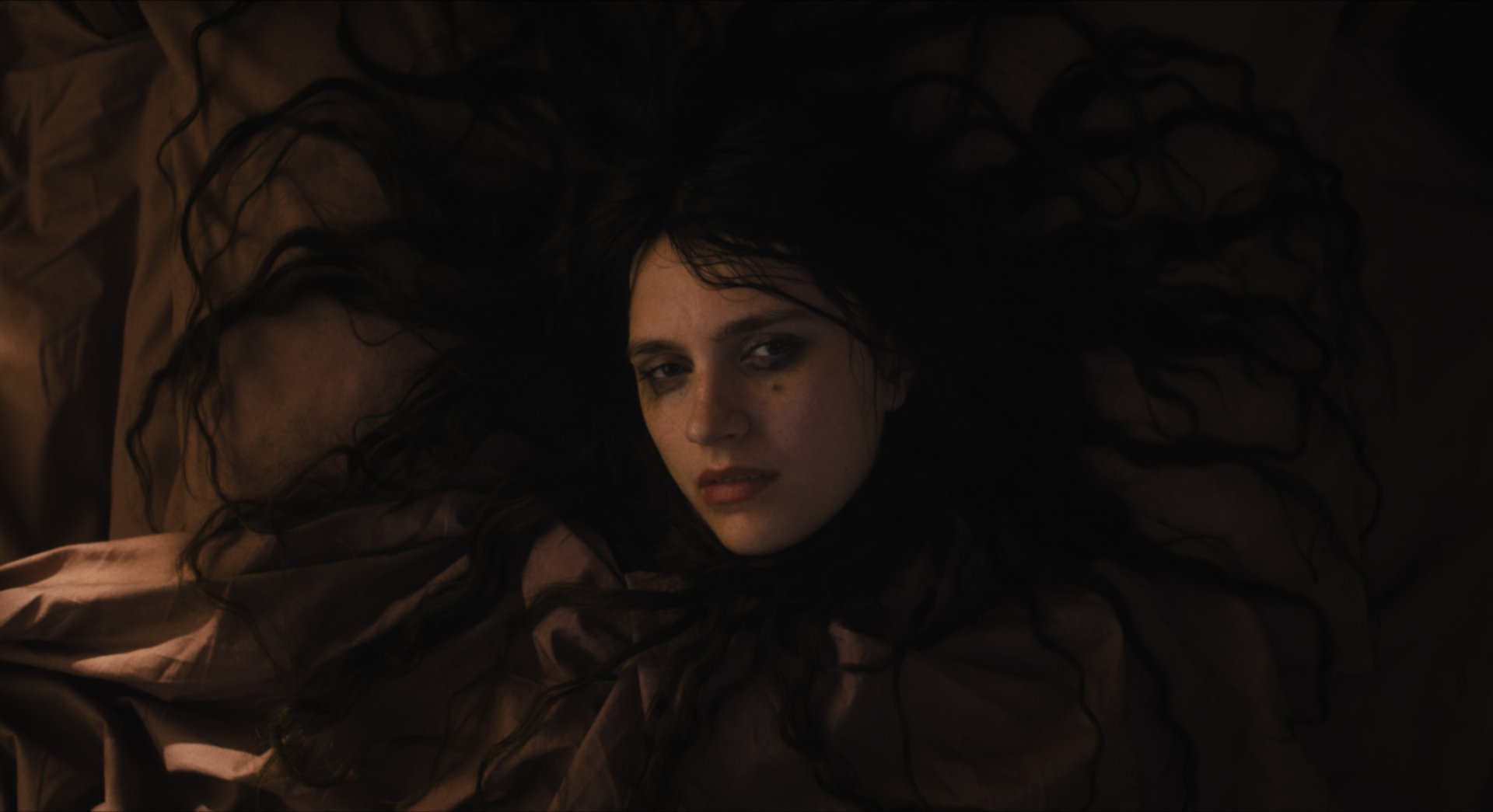 Dramatic HD wallpaper featuring a scene from 'The First Omen' movie, showing a woman with dark, flowing hair spread out, encapsulating the film's eerie atmosphere.