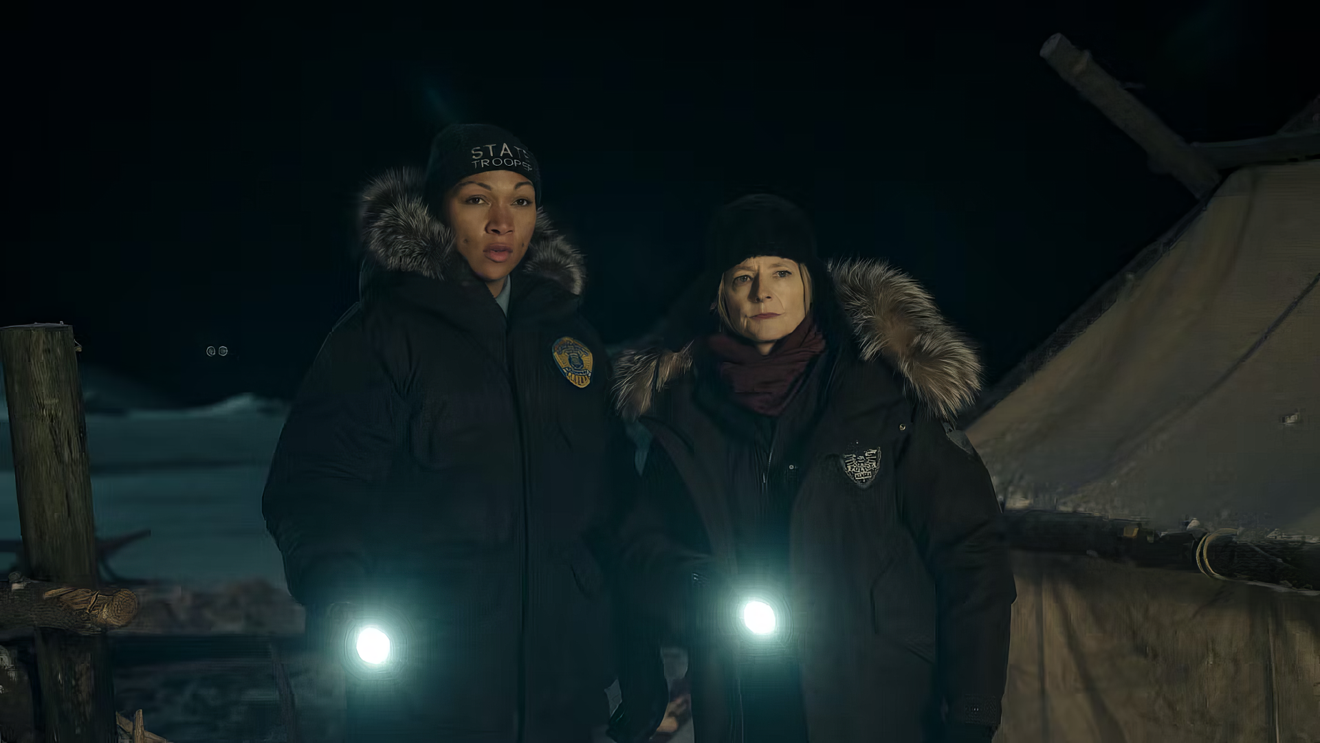 HD wallpaper featuring two characters from the TV show True Detective, clad in winter attire and holding flashlights, with a tent and snowy background.