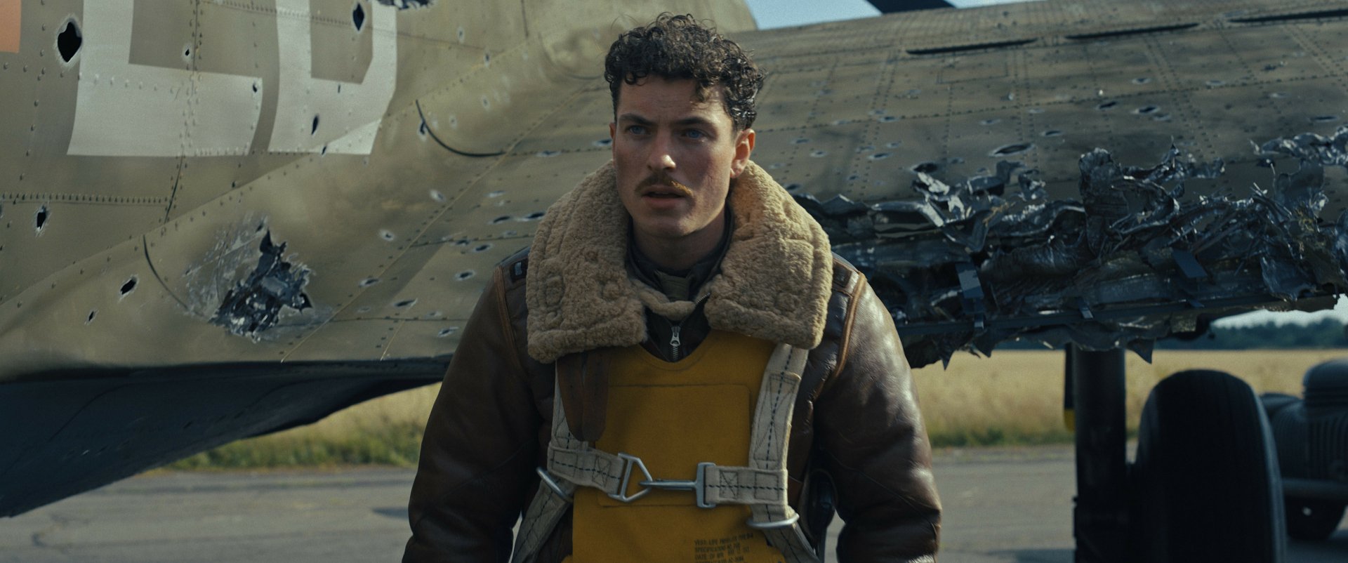 Masters of the Air TV show promotional HD wallpaper featuring a character in pilot attire in front of a wartime aircraft.