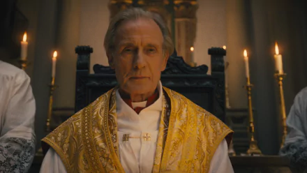 HD desktop wallpaper from The First Omen featuring a somber priest in golden vestments surrounded by candlelight.
