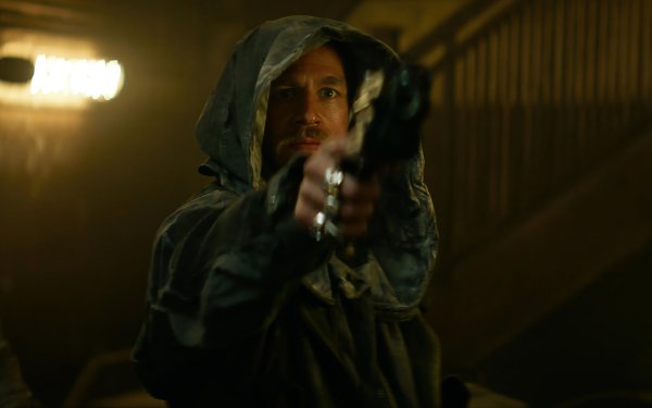 Hooded character aiming a gun in a tense scene from the movie 'Rebel Moon', perfect for HD desktop wallpaper and background.