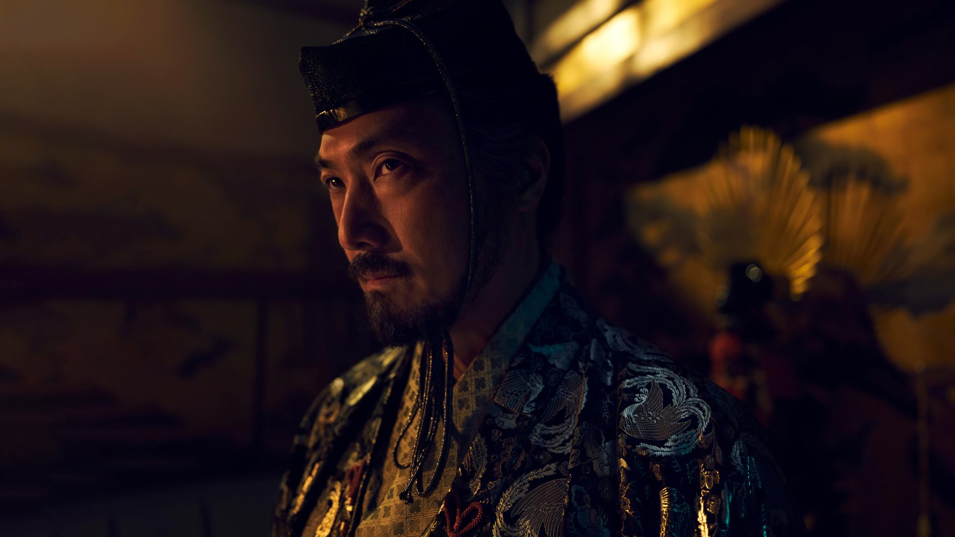 A dramatic HD wallpaper from the TV show Shogun (2024), featuring a character in ornate attire, set against a rich, atmospheric background.