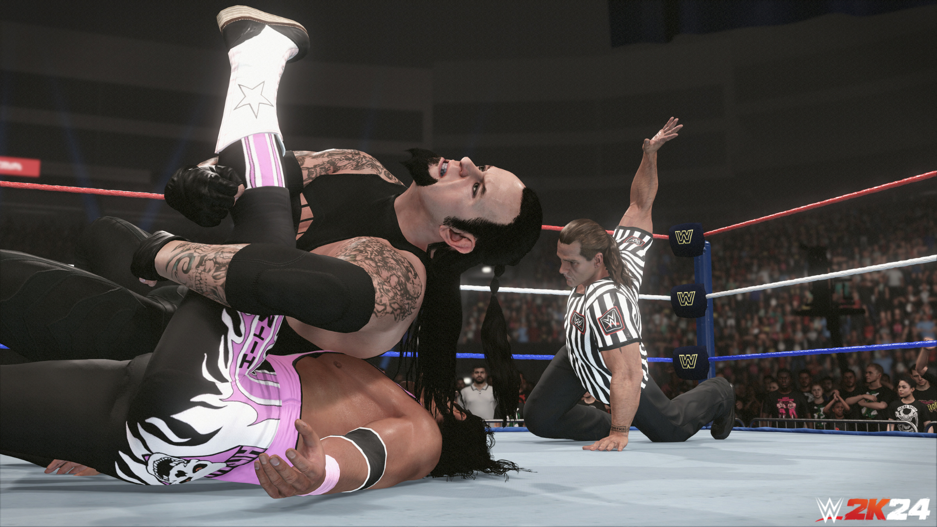 HD desktop wallpaper of WWE 2K24 video game featuring a wrestler performing a pin on an opponent with the referee counting, in a packed arena setting.