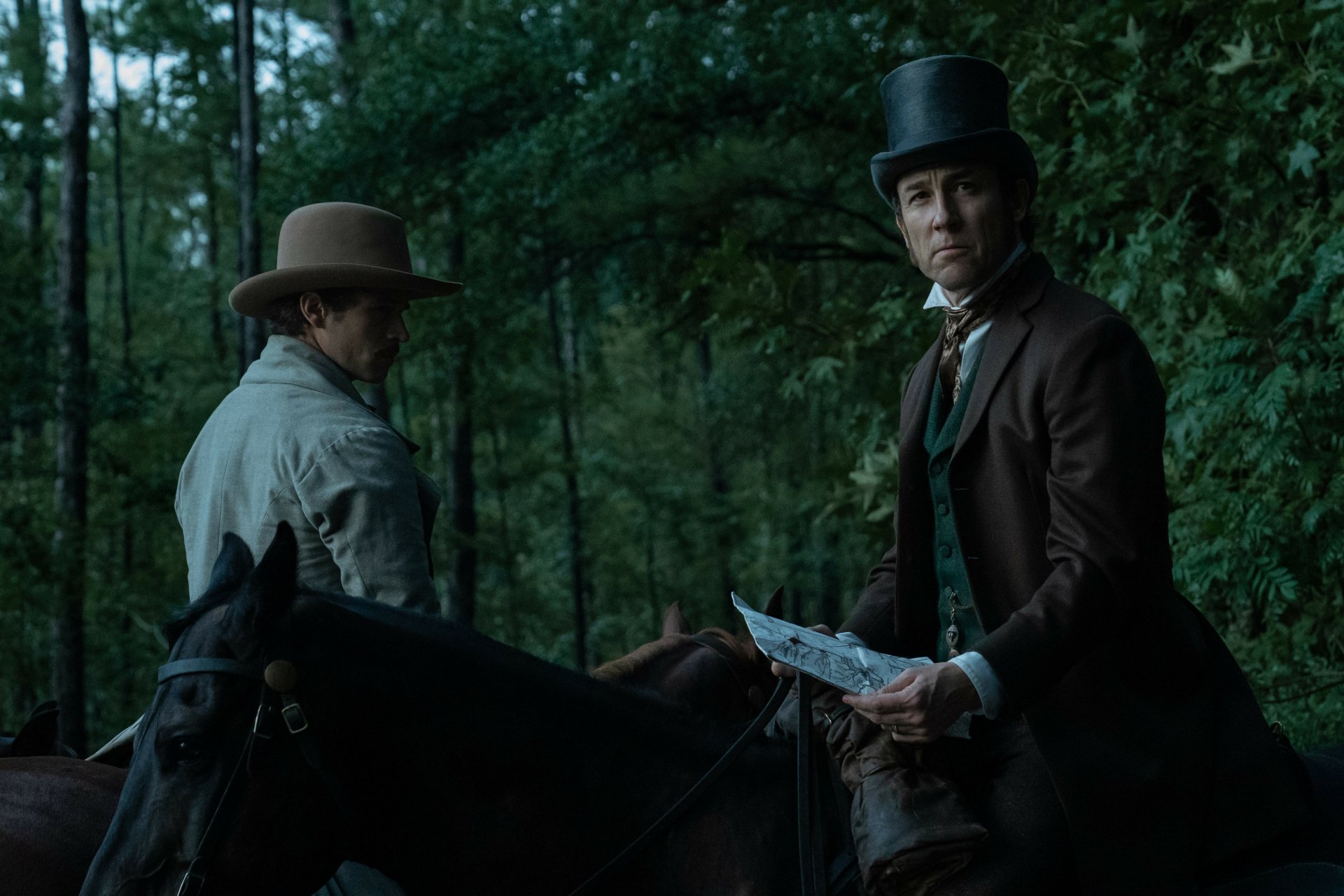HD desktop wallpaper featuring two characters on horseback in a forest scene from the TV show Manhunt (2024).