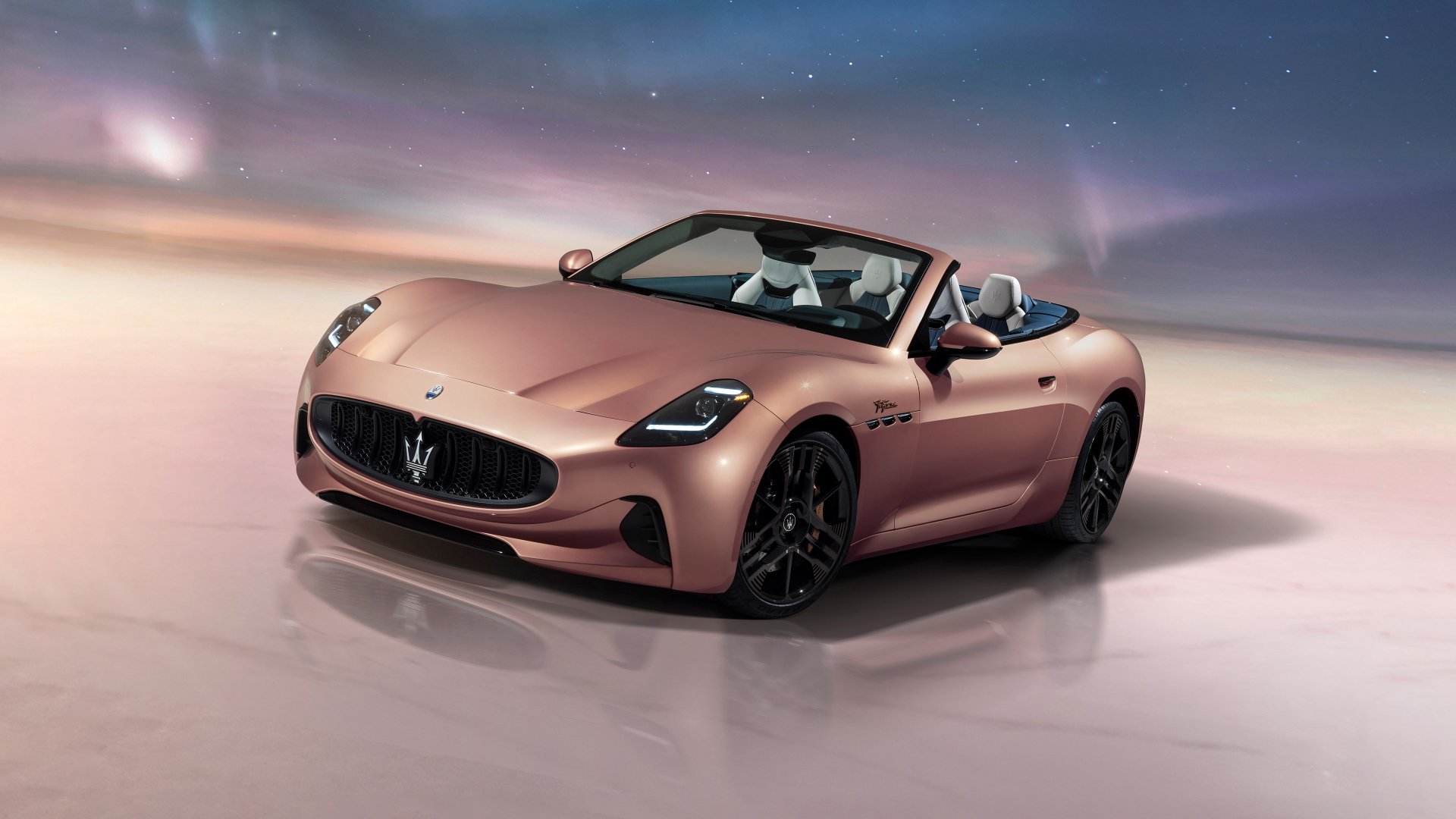 HD wallpaper of a Maserati GranCabrio car with its roof down, parked under a soft glowing light with a blurred background that evokes a sense of speed.