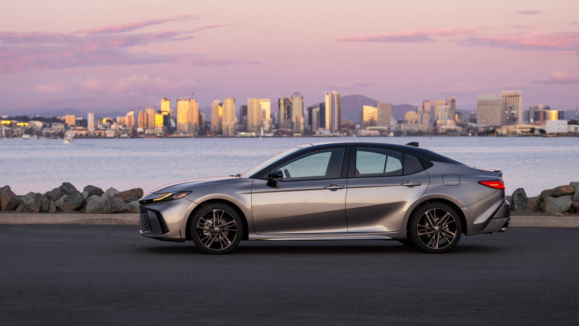 A silver Toyota Camry XSE parked with a city skyline in the background during twilight, used as an HD desktop wallpaper and background.
