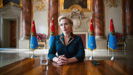 HD desktop wallpaper featuring a scene from the TV show 'The Regime' with a character portrayed by the actress, sitting at an elegant conference table surrounded by flags.