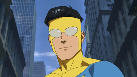 HD wallpaper of Invincible cartoon character from the TV show standing in a cityscape, showcasing the iconic blue and yellow superhero costume.