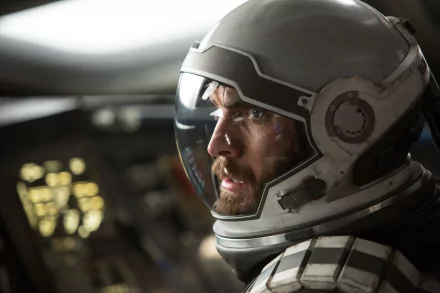 A close-up of an astronaut's intense expression inside a spacecraft from the movie Interstellar, featuring a detailed helmet and cockpit controls, set against a cinematic background.