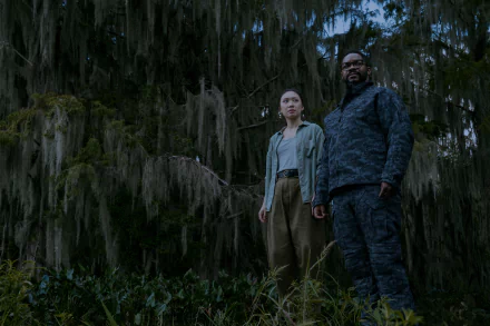 A scene from the TV show 3 Body Problem, featuring two characters standing amidst dense, moss-covered trees, set against a moody, atmospheric backdrop.