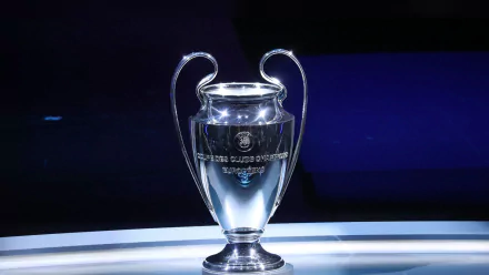 HD wallpaper featuring the prestigious UEFA Champions League trophy illuminated against a dark background.