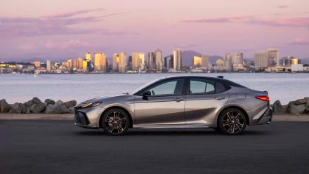 A silver Toyota Camry XSE parked with a city skyline in the background during twilight, used as an HD desktop wallpaper and background.