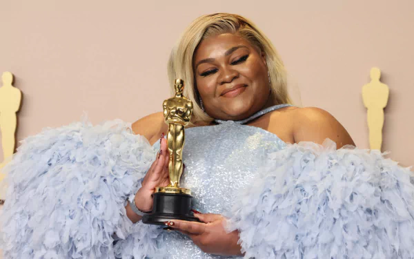 Davine Joy at the Academy Awards holding an Oscar, in a feathered blue dress—HD wallpaper.