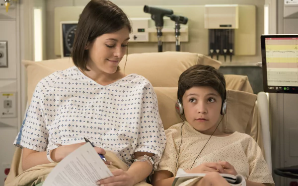 HD desktop wallpaper featuring a scene from the TV show Grey's Anatomy with a woman sitting beside a young patient in a hospital setting.