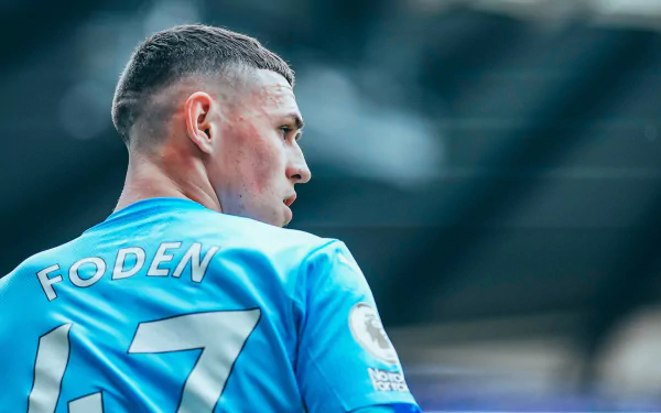 HD wallpaper of Phil Foden in Manchester City F.C. soccer kit, focused on the pitch.