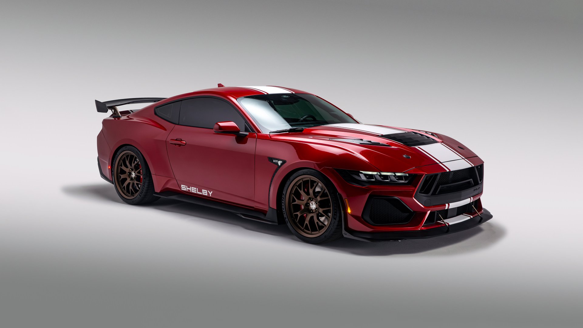 HD desktop wallpaper featuring a red Shelby Super Snake muscle car, showcasing a sleek design with black and gold trim.