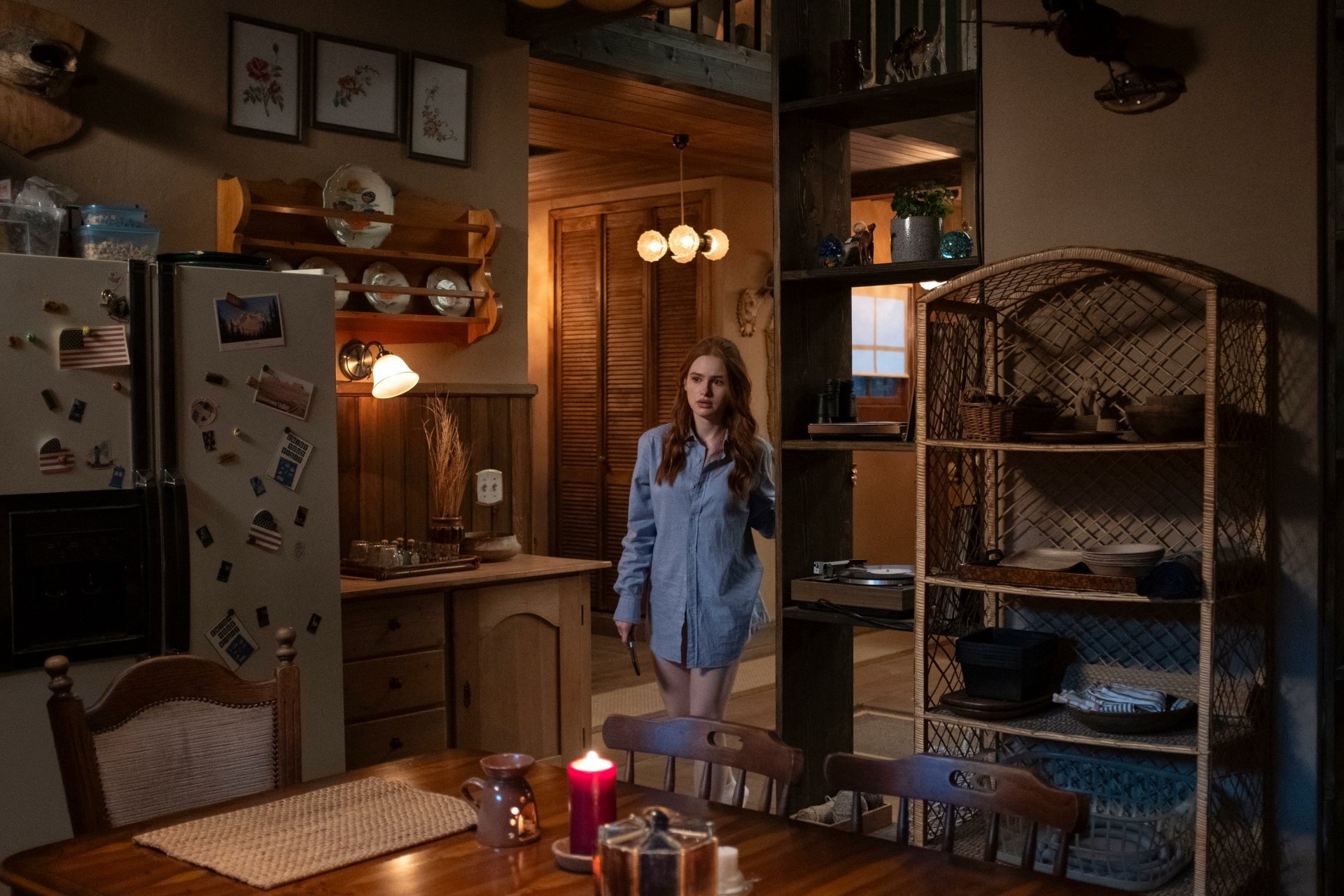 HD desktop wallpaper featuring Madelaine Petsch from the movie The Strangers: Chapter 1. She stands in a cozy, dimly lit kitchen, creating an eerie yet intriguing atmosphere.