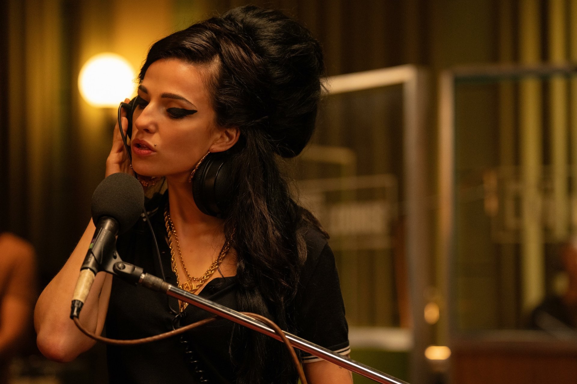 A high-definition desktop wallpaper from the movie Back to Black, featuring Amy Winehouse in a recording studio with her signature beehive hairstyle and makeup, singing into a microphone.