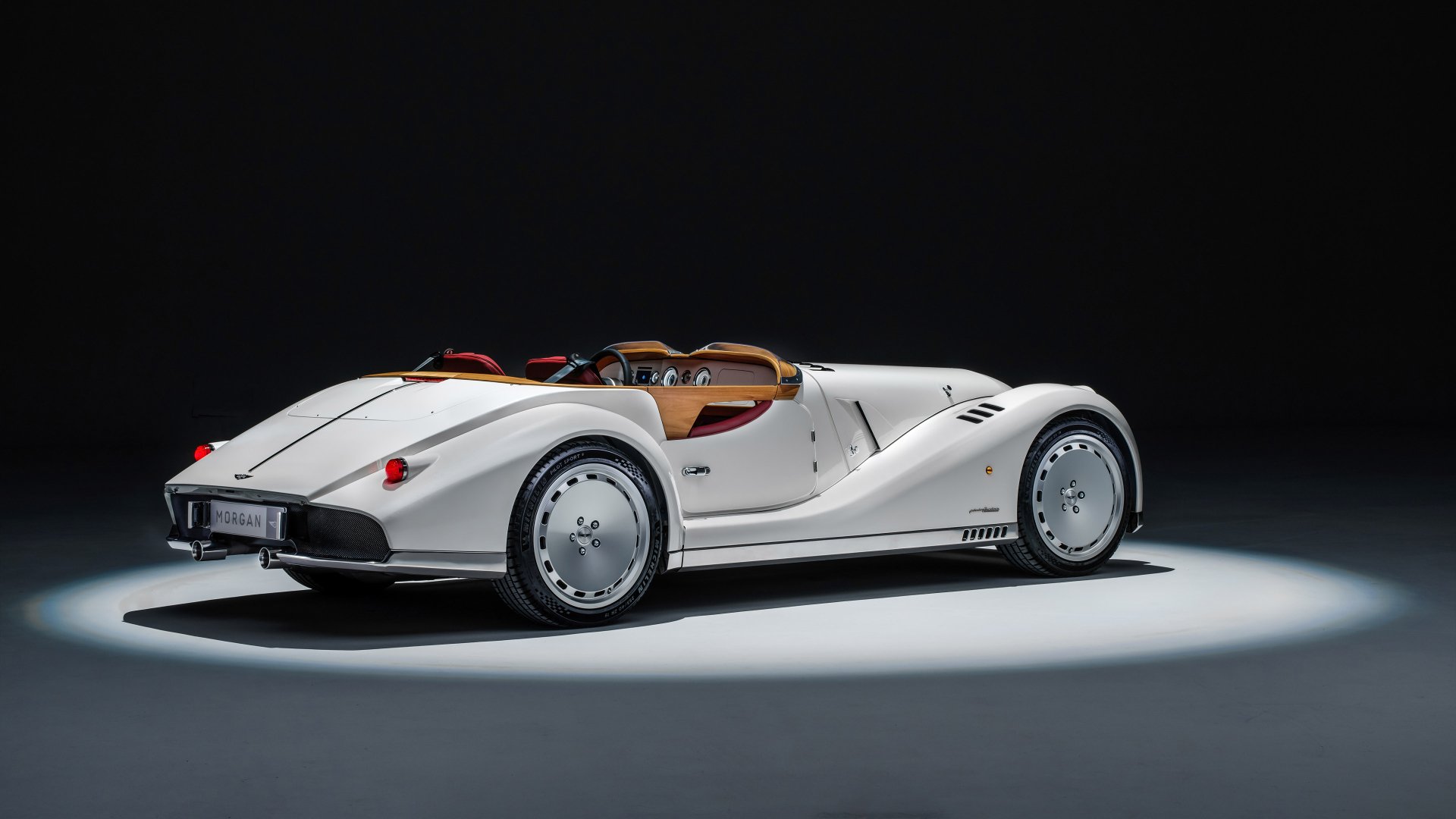 HD wallpaper featuring a sleek, white Morgan Midsummer car, elegantly illuminated against a dark background.