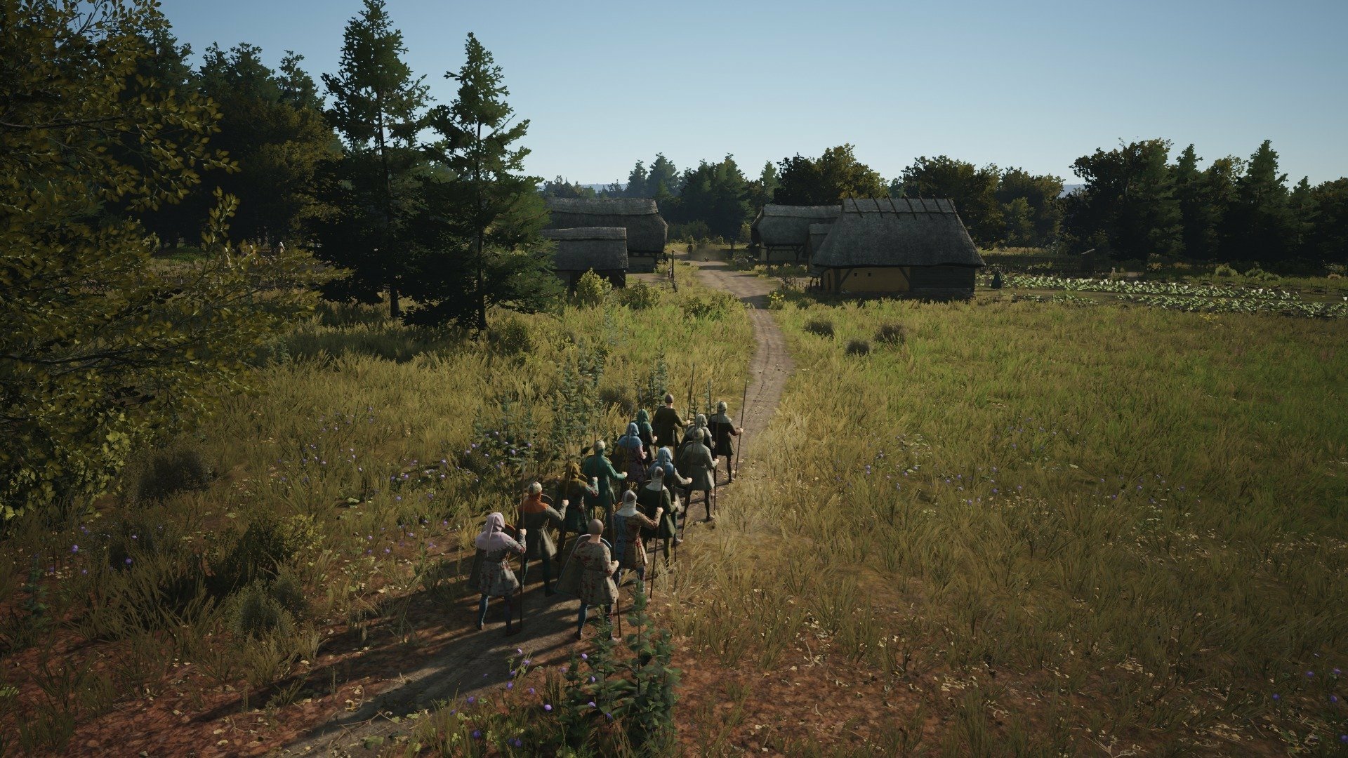 HD wallpaper and background from the video game Manor Lords, featuring a medieval village path with people walking through a lush, green landscape under a clear sky.