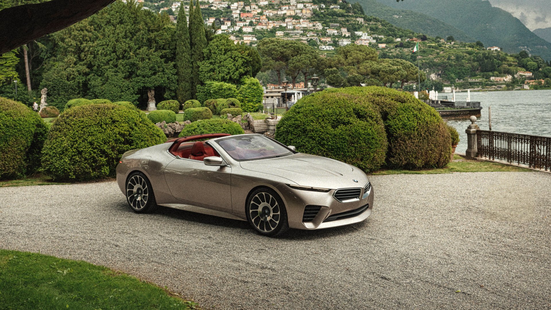 A high-definition wallpaper featuring a sleek BMW Skytop parked on a gravel path, set against a picturesque backdrop of lush greenery and waterfront scenery.