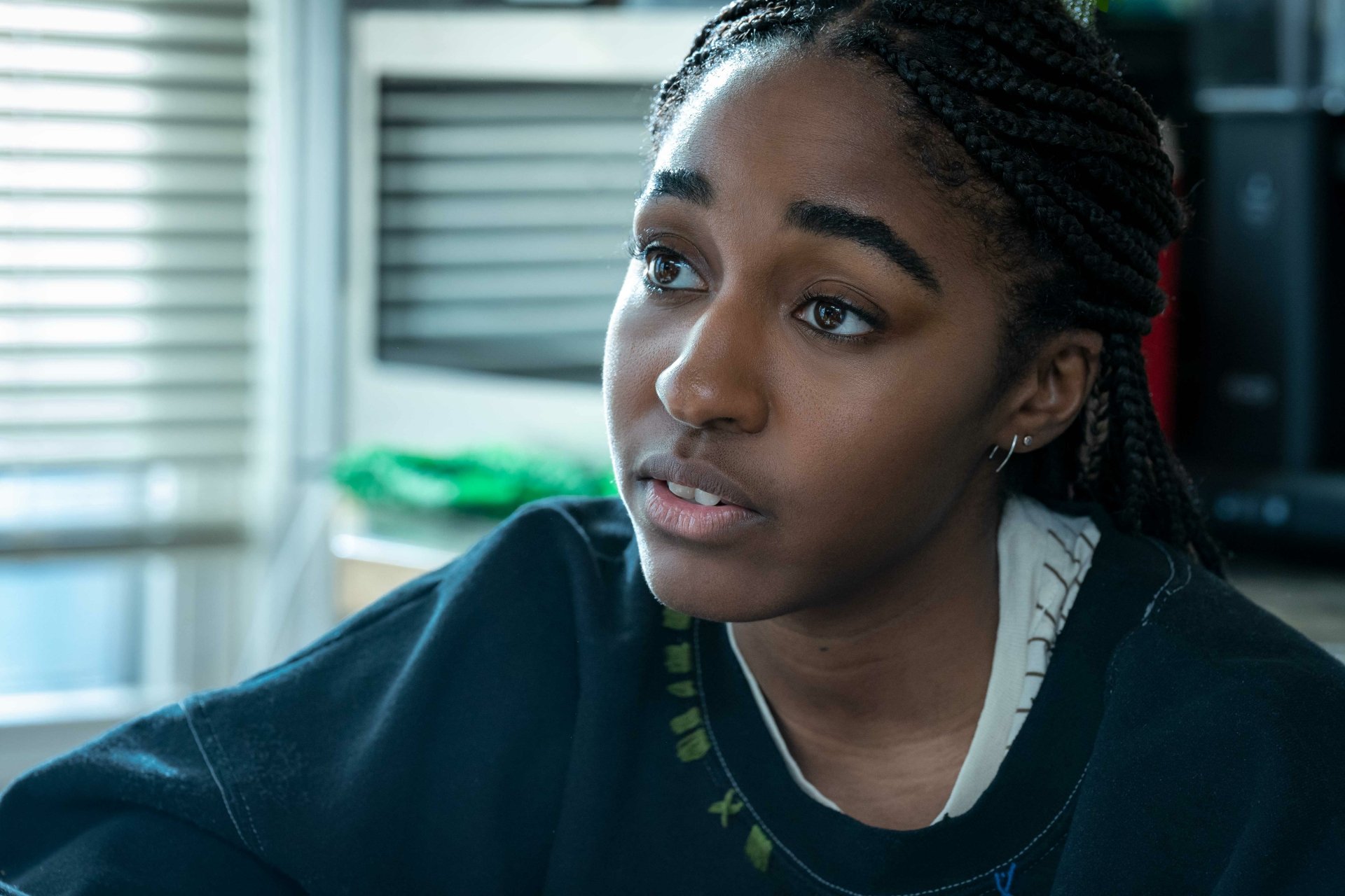HD desktop wallpaper and background featuring a character from the TV show The Bear, showcasing a young woman with braided hair and a contemplative expression in a softly lit interior setting.