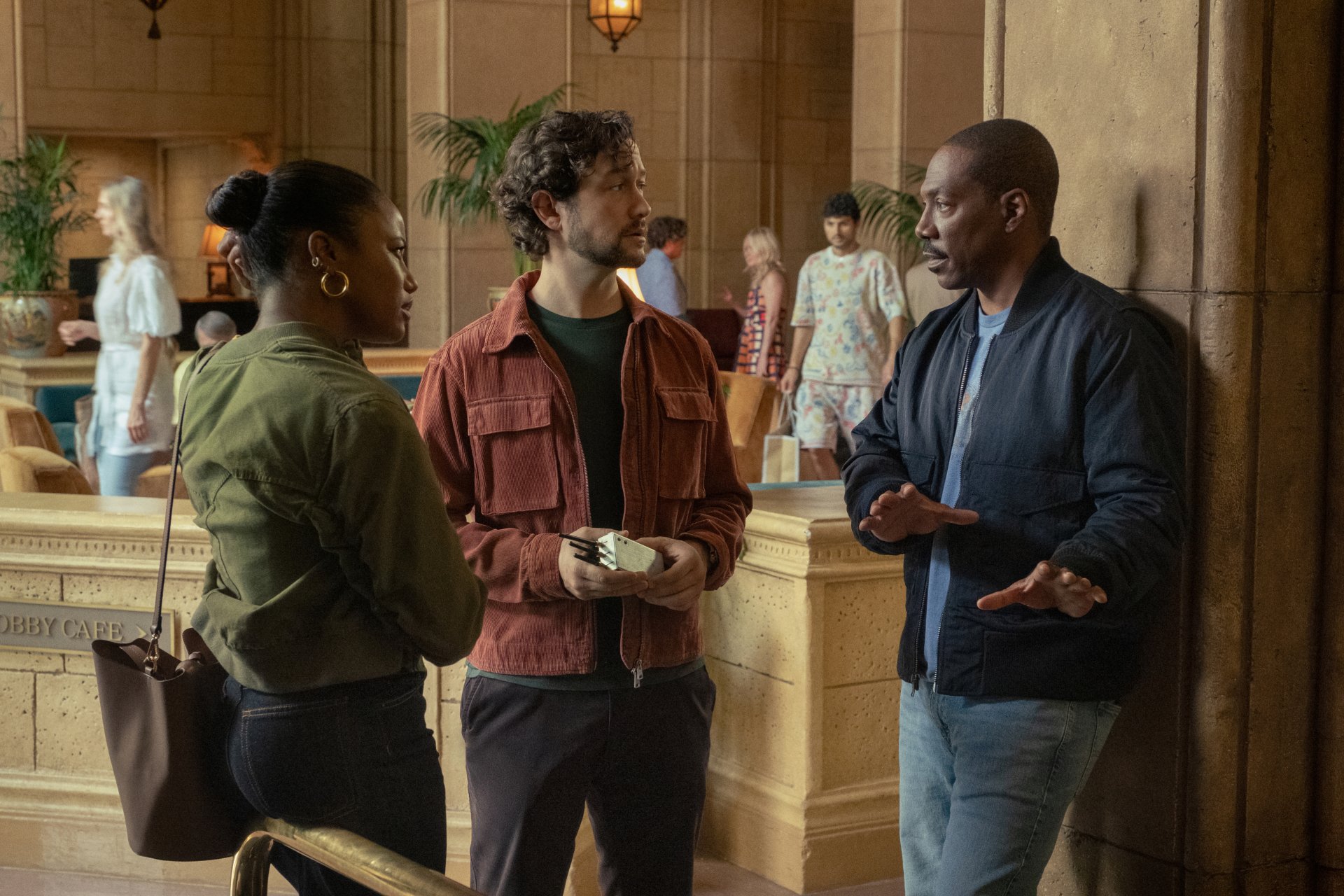 HD desktop wallpaper from the movie Beverly Hills Cop: Axel F, showing three individuals engaged in conversation in a lavish interior setting.