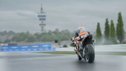 HD desktop wallpaper featuring a MotoGP 24 motorcycle racing on a wet track, with spray from the tires and a tower in the background.